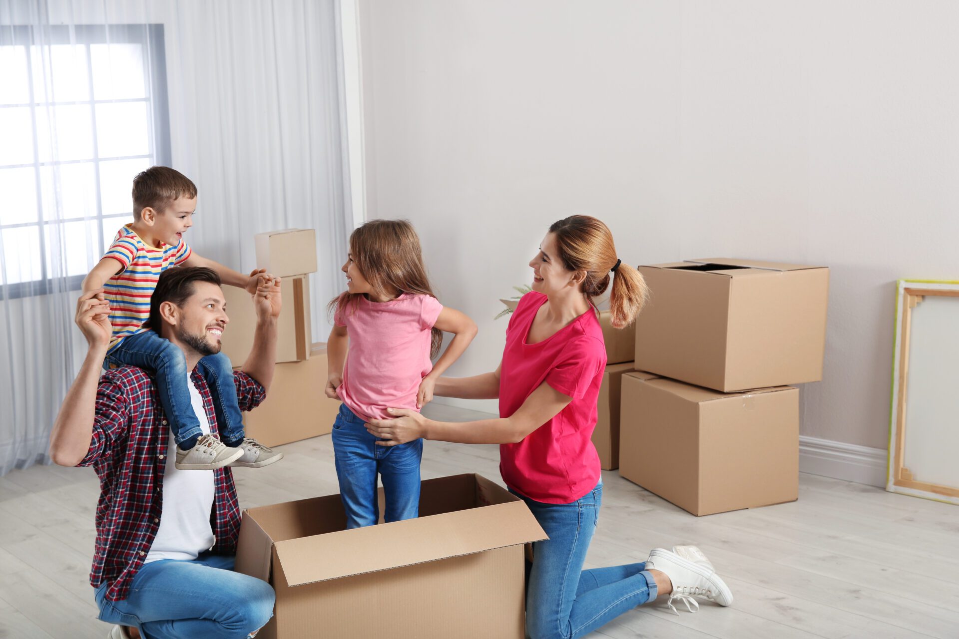 Happy family playing with cardboard box in their new house. Moving day